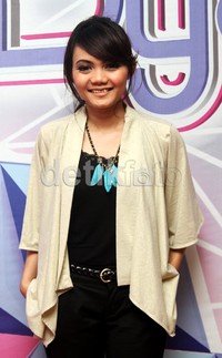 Rina Nose tampil mengenakan tanktop hitam yang dipadukan dengan outwear krem dan kalung biru. GusmundetikFoto.