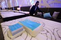 Seorang SPG tengah merapikan tempat tidur yang dipamerkan di 'Furniture dan Interior Expo 2013'.