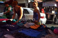 Dua orang wisatawan melihat-lihat pakaian yang dijual di trotoar di kawasan Pathumwan, Siam, Bangkok, Thailand.