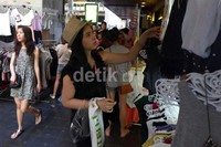 Seorang wisatawan melihat pakaian yang akan dibelinya.