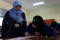 Seorang guru mengawasi para siswa yang sedang mengisi soal try out UN.