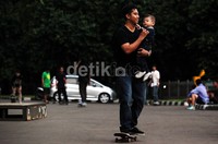 Aksi seorang bapak bersama anaknya di atas skateboard.