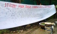 Selembar spanduk putih berukuran 1 x 3 meter yang di atasnya terdapat tulisan dari cat semprot merah  11 Ribu Tanda Tangan Dukungan untuk 11 Prajurit Kopassus. Syarifah/detikcom     