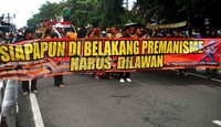 Para pendemo membentangkan spanduk di tengah jalan.