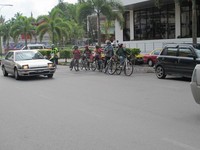 Para peserta menunggu waktu menyeberang. Tak sulit untuk menyeberang jalan di Kota Kuching, naik sepeda sekalipun. Walaupun banyak mobil melaju kencang, jalanan cukup lengang. Mereka juga dengan murah hati mau berhenti kalau tangan kami melambai sebelum menyeberang. (Sastri/detikTravel)