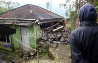 Seorang warga mengabadikan rumah yang rusak dengan ponsel. Arbi Anugrah/detikFoto.