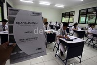 Seorang guru membagikan soal-soal ujian.