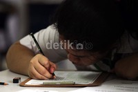 Seorang siswa tampak teliti menjawab soal-soal ujian.