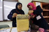 Dua orang guru membagikan soal-soal ujian.
