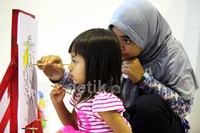 Seorang anak didampingi orangtunya, tengah belajar menggambar dan mewarnai di atas kanvas.