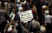 Seorang jamaah membawa poster turut beduka cita atas wafatnya Uje.