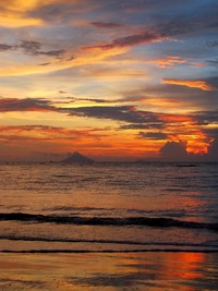 Dari kejauhan, terlihat anak Gunung Krakatau yang berbentuk segitiga. Saat sore, gunung tetap terlihat dan jadi semakin indah dengan latar belakang langit jingga (Shafa/detikTravel)