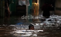 Seorang anak bermain di air banjir.
