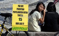  Dua remaja putri, tengah duduk dibelakang poster bertuliskan Pak SBY, Penentuan Penyelamatan Hutan Tinggal 15 Hari Lagi!!!,