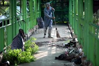 Petugas membersihkan sampah dan alang-alang di jembatan penyeberangan orang Jalan Asia Afrika.