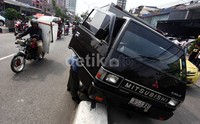 Mobil boks bernomor polisi B 9159 FU tersebut nangkring di atas pembatas jalan.