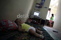 Seorang bayi tampak digeletakan di ruang tamu rusun tersebut saat orang tuanya berbenah di dapur.