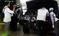 Penyidik KPK membuka kap mobil dan memeriksa mesin mobil.