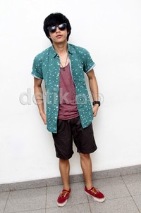 Ia tampil santai mengenakan kaus merah, kemeja hijau, celana pendek coklat, dan sepatu merah. Gus Mun/detikHOT.