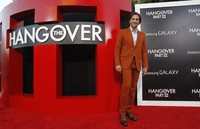 Bradley Cooper tampil necis, mengenakan setelan jas berwarna oranye tua di red carpet. REUTERS/Mario Anzuoni.