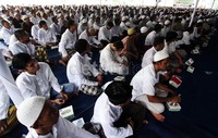 Para napi duduk rapat-rapat di bawah tenda biru yang dipasang di lapangan tersebut.