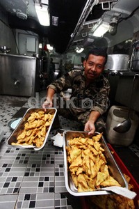 Seorang prajurit TNI AL menunjukkan makanan yang siap untuk dihidangkan.