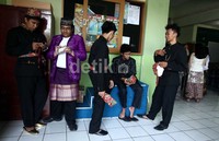 Para siswa yang memakai pakaian adat menunggu pengumuman dengan berbincang di depan sekolah.
