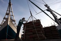 Seorang pekerja memindahkan semen dari kapal ke truk.