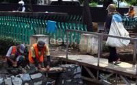 Pekerja meninggikan tanggul kali Lio.