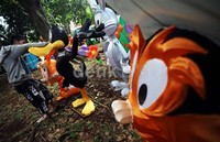 Seorang pekerja melakukan pengecetan pada lampion-lapion berbentuk tokoh kartun.