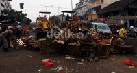 Untuk menyingkirkan tumpukan kayu dari lapak-lapak tersebut, petugas mengerahkan 2 alat berat.