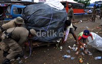 Petugas membantu pedagang memindahkan barang daganganya.