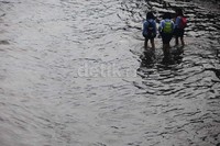 Anak-anak yang baru pulang sekolah menerobos banjir.
