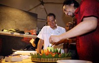 Gita Wirjawan ditawari untuk mencicipi tumpeng yang baru saja dipotong sebagai tanda syukur dibukanya gerai milik Piyu itu.