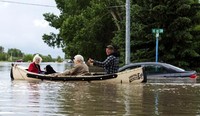 Dua orang warga dievakuasi dengan perahu. Reuters/Mike Sturk.