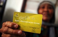 Seorang warga menunjukkan Kartu Perlindungan Sosial sebelum mengambil Bantuan Langsung Sementara Masyarakat (Balsem).
