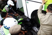 Petugas kepolisian berusaha mengevakuasi motor yang terlindas bus. Lamhot Aritonang/detikFoto.