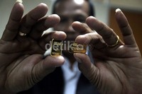 Seorang pegawai menunjukkan emas pegadaian yang dicetak di Perum Peruri, Karawang, Jawa Barat, Senin (24/6/2013).