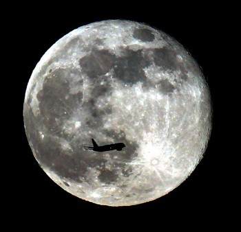 Foto pesawat yang melintas di depan supermoon ini diabadikan di atas langit Monterey Park, California. (kredit foto: Nick Ut/Associated Press)