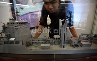Seorang pengunjung melihat miniatur kapal perang yang dipamerkan.