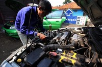 Seorang montir mengecek mesin mobil.