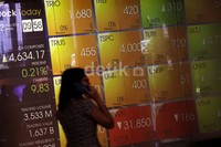 Seorang melintas di depan papan bursa yang terpampang di halaman Bursa Efek Indonesia, Jakarta, Jumat (2/8/2013) petang.