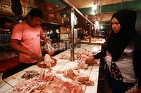 Seorang pedagang ayam melayani pembeli.