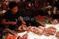 Seorang pedagang memotong ayam pesanan menjadi beberapa bagian.