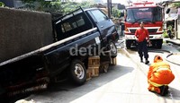 Karena menghalangi mobil pemadam kebakaran, sebuah mobil bak erpaksa digeser hingga jatuh ke got. Lamhot Aritonang/detikFoto.