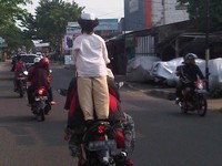 Seorang anak berdiri di belakang motor. Foto Paulus Ivan Gunawan.