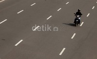 Seorang pengendara motor melaju di jalan sudirman, tampak jalan tersebut masih lengang