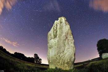 Sebuah meteor melaju cepat di langit atas monumen kuno di Avebury, Inggris. (kredit foto: Press Association)