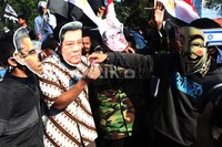 Dalam aksi itu dua orang pendemo memakai topeng bergambar SBY dan Obama.