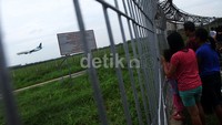 Warga menyaksikan pesawat mendarat di kawasan Bandara Internasional Soekarno Hatta, Tangerang, Kamis (15/08/2013).